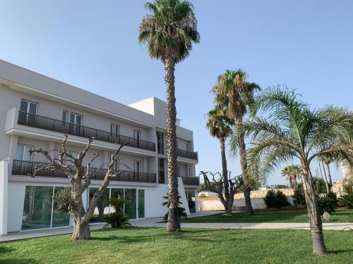 a building with palm trees in front of it at Hotel Posidonia in Porto Cesareo