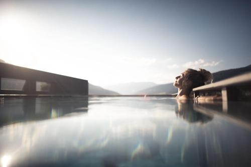 un perro está sentado en una piscina en Alpinhotel Keil, en Valdaora