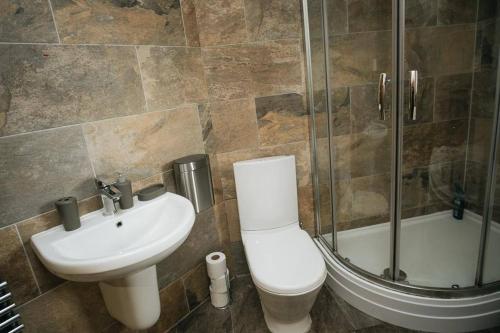 La salle de bains est pourvue de toilettes, d'un lavabo et d'une douche. dans l'établissement WILSONS COTTAGE - 2 Bed Classic Cottage located in Cumbria with a cosy fire, à Camerton