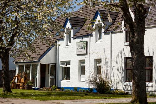 una casa blanca con techo de gambrel en Eilean Donan Guest House, en Ullapool
