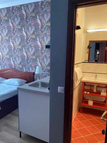 a bathroom with a sink and a bed and a mirror at Hotel Kert FREE PARKING in Rīga