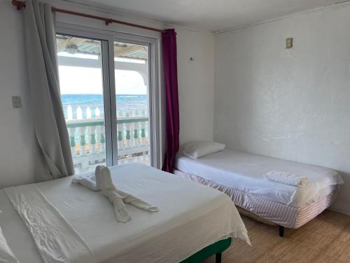 Duas camas num quarto com uma janela grande em The Wave Hostel Corn Island em Ilhas do Milho