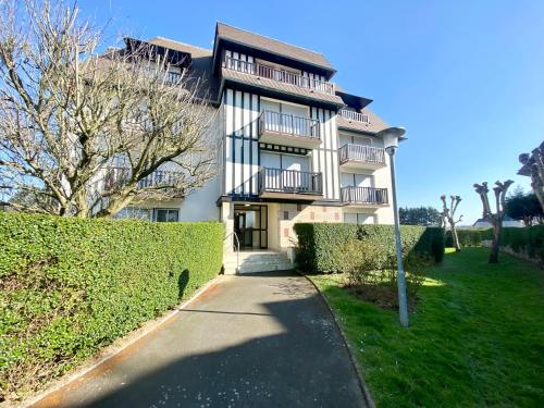 um grande edifício branco com uma sebe à sua frente em Superbe appartement avec jardin ensoleillé em Blonville-sur-Mer