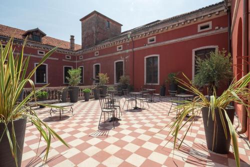 a courtyard with tables and chairs and potted plants at Hotel Palazzo Martinelli Dolfin in Venice