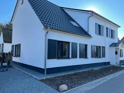 a white house with black windows on a street at Naturidyll Mariendorf - Ferienwohnung Hagensche Wiek in Mariendorf