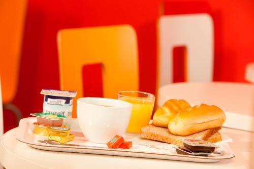 a plate of food with a sandwich and orange juice at Premiere Classe Reims Sud - Bezannes in Reims