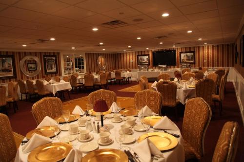 a dining room with tables and chairs and a screen at Salvatores Grand Hotel in Williamsville