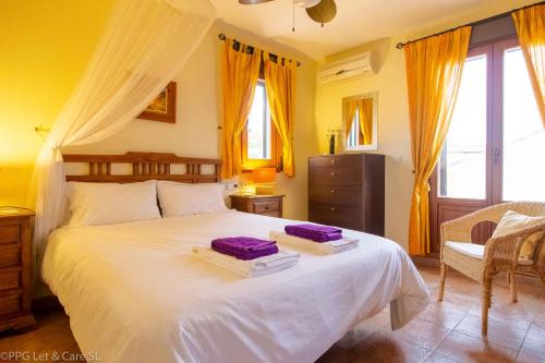 a bedroom with a large white bed with purple sheets at (ROU002) Cómoda Casa con Puerta a la Piscina in Ayamonte