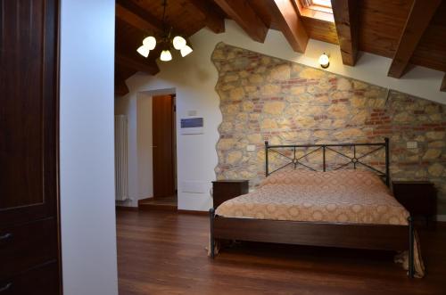 a bed in a room with a stone wall at Agriturismo Alla Corte in Vicenza