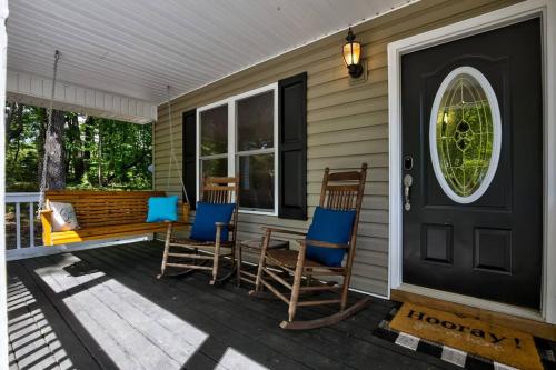a porch with rocking chairs and a black door at Less than 3 miles to Downtown with firepit in Ellijay