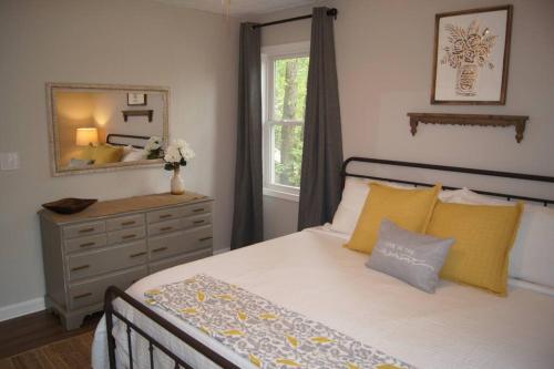 a bedroom with a bed with yellow pillows and a mirror at Less than 3 miles to Downtown with firepit in Ellijay