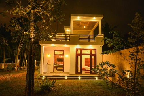 a small white house with lights in the night at Yehen's Villa in Unawatuna