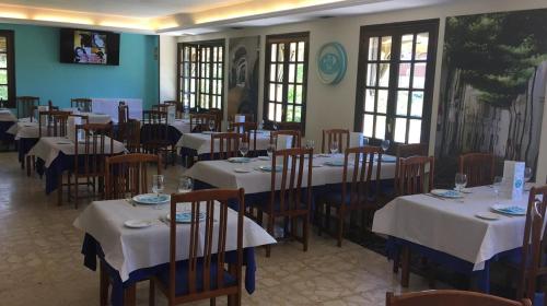 jadalnia z białymi stołami, krzesłami i oknami w obiekcie Hostal Asador Julian w mieście Brunete