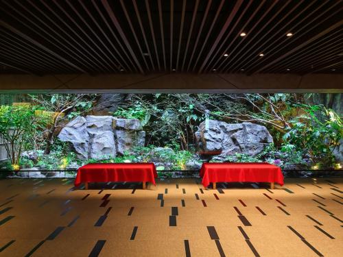 two red tables in front of a wall of plants at Solaria Nishitetsu Hotel Kyoto Premier in Kyoto