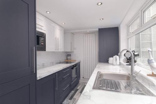 a white kitchen with a sink and a microwave at Hope Street in Filey