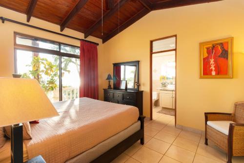 a bedroom with a bed and a chair and a window at Luxury Flamingo villa with outdoor bar - pool and magnificent views in Playa Flamingo