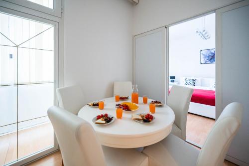 a white dining room with a white table and chairs at Bright and Modern 1BDR Apartment in the Center in Sarajevo