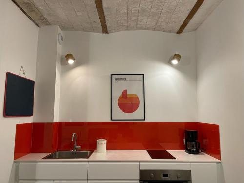 a kitchen with a sink and a red and white wall at La muche 2 in Marquillies