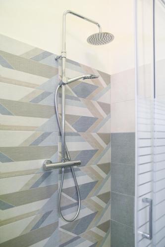 a shower in a bathroom with a geometric tile floor at Xenia Home in Reggio Calabria