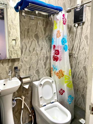 a bathroom with a toilet and a sink and a shower curtain at Haus of Emerald - Astana by Ollie in Mactan