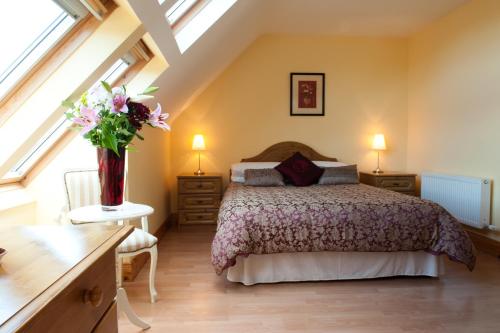 Eas Dun Lodge في دونيجال: غرفة نوم بسرير و إناء من الزهور