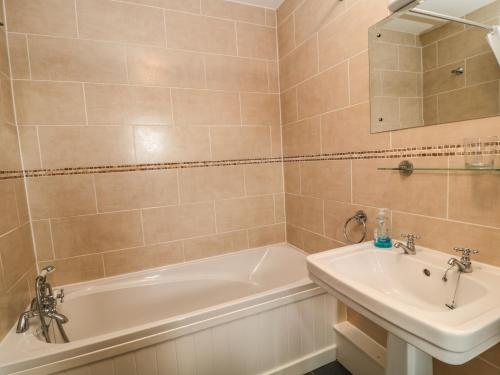 une salle de bain avec une baignoire et un lavabo dans l'établissement Honey Bee Cottage, à Holsworthy