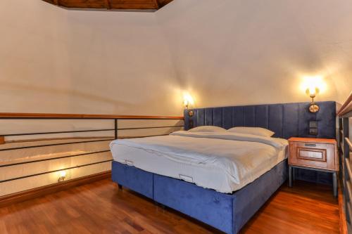 a bedroom with a blue bed with a wooden headboard at Azur Hotel in Cıralı