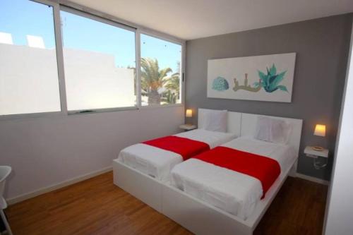 プエルト・デル・カルメンにあるCasa Playa Los Pocillos in Puerto del Carmenのベッドルーム(赤いシーツを使用した白い大型ベッド1台付)