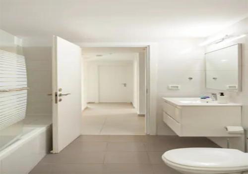 a white bathroom with a toilet and a sink at O&O Group-Fresh 3BR APT 32 Floor See View Tower in Bat Yam