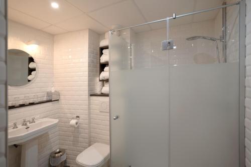 a bathroom with a shower and a toilet and a sink at Hotel Litteraire Marcel Ayme, BW Premier Collection in Paris