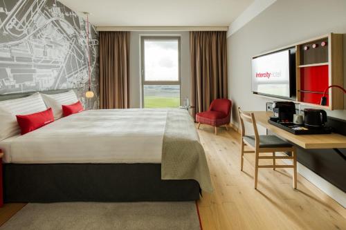 a hotel room with a bed and a desk and a television at IntercityHotel Amsterdam Airport in Hoofddorp