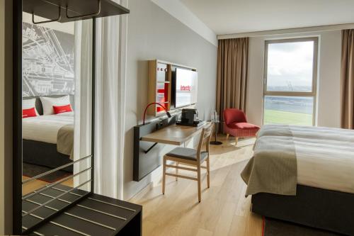 a hotel room with a bed and a desk and a bedroom at IntercityHotel Amsterdam Schiphol Airport in Hoofddorp