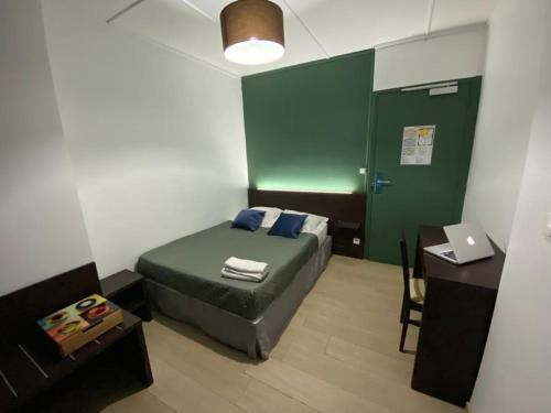 a bedroom with a bed and a desk with a laptop at Citadel Hôtel in Calais