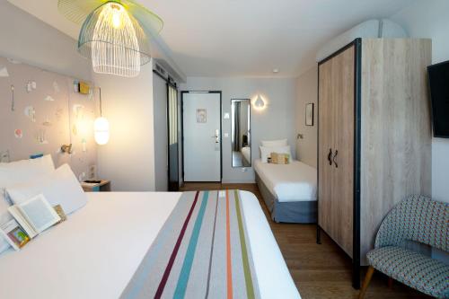 a bedroom with a large white bed and two chairs at Hotel Litteraire Marcel Ayme, BW Premier Collection in Paris