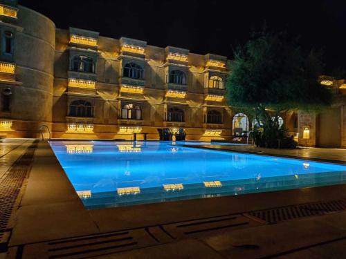 a large swimming pool in front of a building at night at Hotel Golden Haveli in Jaisalmer