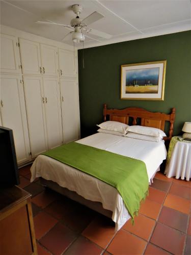 a bedroom with a large bed with a green wall at Fountain Baths Guest Cottages in Barberton