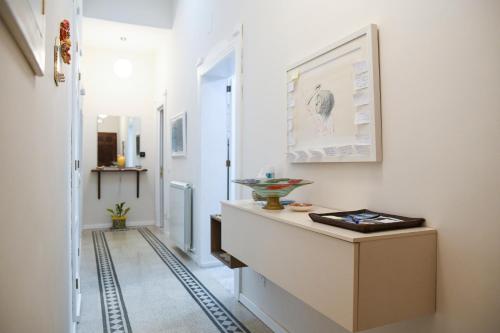 a hallway with white walls and a staircase with a table at Xenia Home in Reggio Calabria