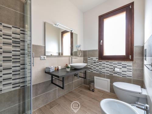 une salle de bain avec un lavabo, des toilettes et un miroir dans l'établissement Villa Monica - Suites, à Iglesias