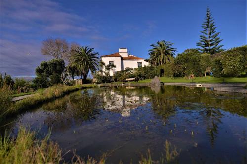 a large pond in front of a building with palm trees at Quinta do Bom Despacho in Ponta Delgada