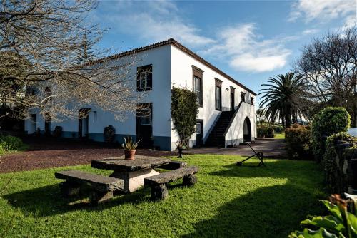 a white building with a picnic table in the yard at Quinta do Bom Despacho in Ponta Delgada
