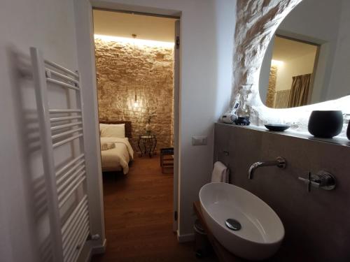 un bagno con lavandino, specchio e letto di Aracoeli 20 a Cassano delle Murge