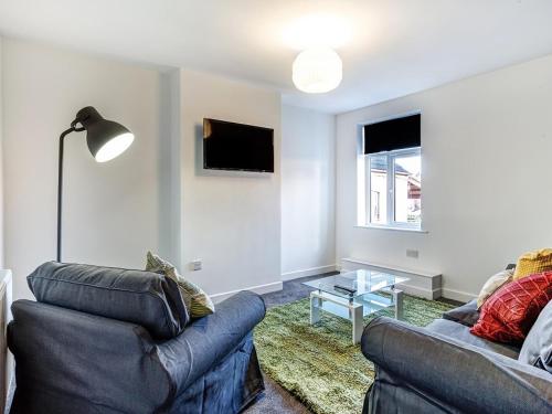 a living room with a couch and a table and a tv at Townhouse PLUS @ 166 Edleston Road Crewe in Crewe