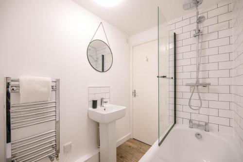 uma casa de banho branca com um lavatório e um espelho em Lily Cottage Leiston em Leiston