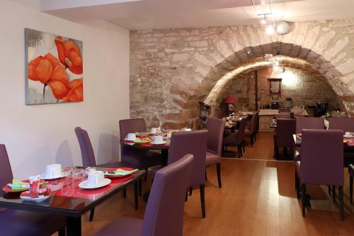 a dining room with tables and chairs and a stone wall at Le Pavillon Saint-Martin in Souillac