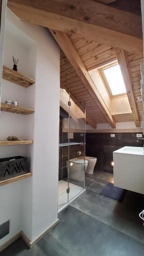 uma casa de banho com paredes brancas e um tecto com uma clarabóia em Mansarda la Baita em Madonna di Campiglio