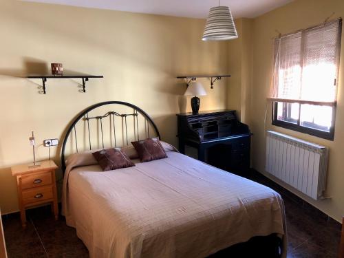 1 dormitorio con cama, escritorio y ventana en Casa en el corazón de Gredos, amplia y agradable., en Navacepeda de Tormes