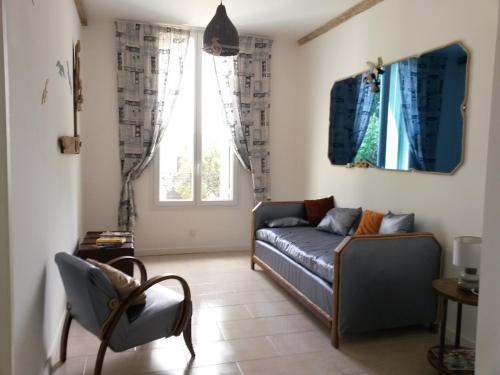 a living room with a couch and two windows at Gîtes "tout au sud de la France" in Pomérols