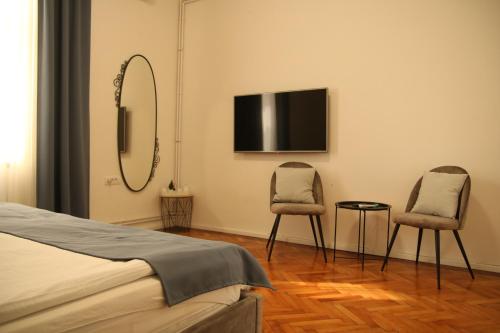 ein Schlafzimmer mit 2 Stühlen und einem TV an der Wand in der Unterkunft Natalie's Royal M in Belgrad
