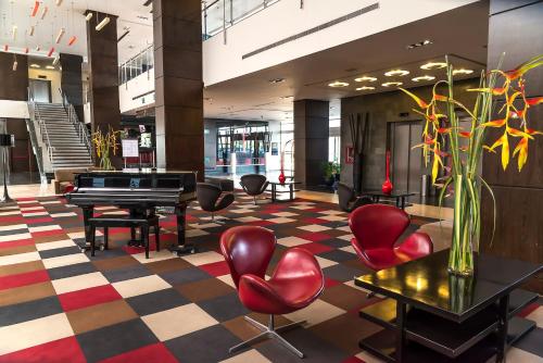 a lobby with a piano and chairs in a building at Hotel Trinitarias Suites in Barquisimeto
