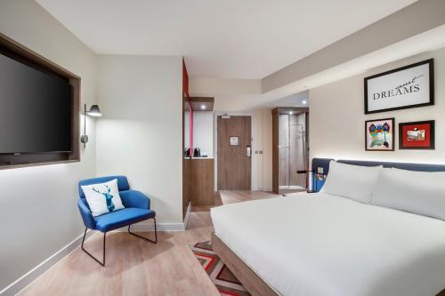 a bedroom with a bed and a tv and a blue chair at Hampton By Hilton Bath City in Bath